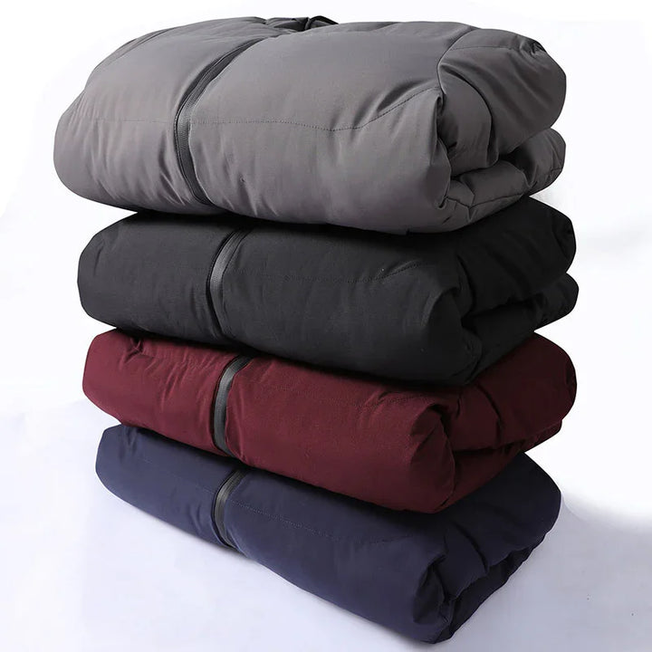 Stack of folded puffer jackets in gray, black, maroon, and navy blue on white background