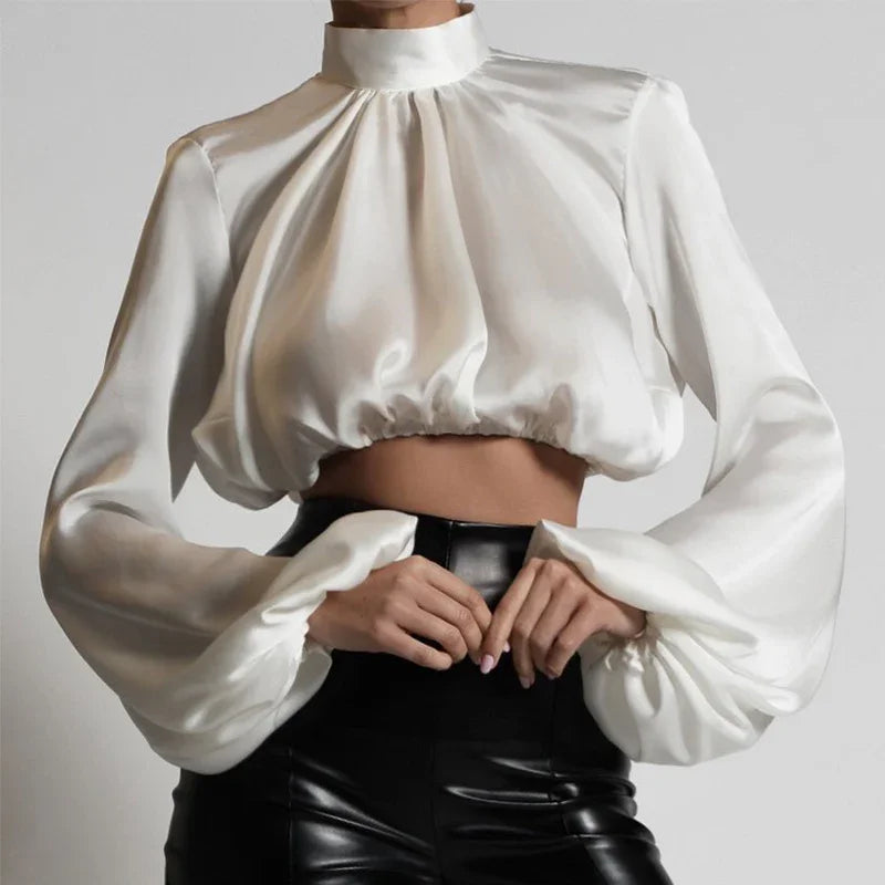 White satin cropped blouse with high neck and puffed long sleeves paired with black leather pants