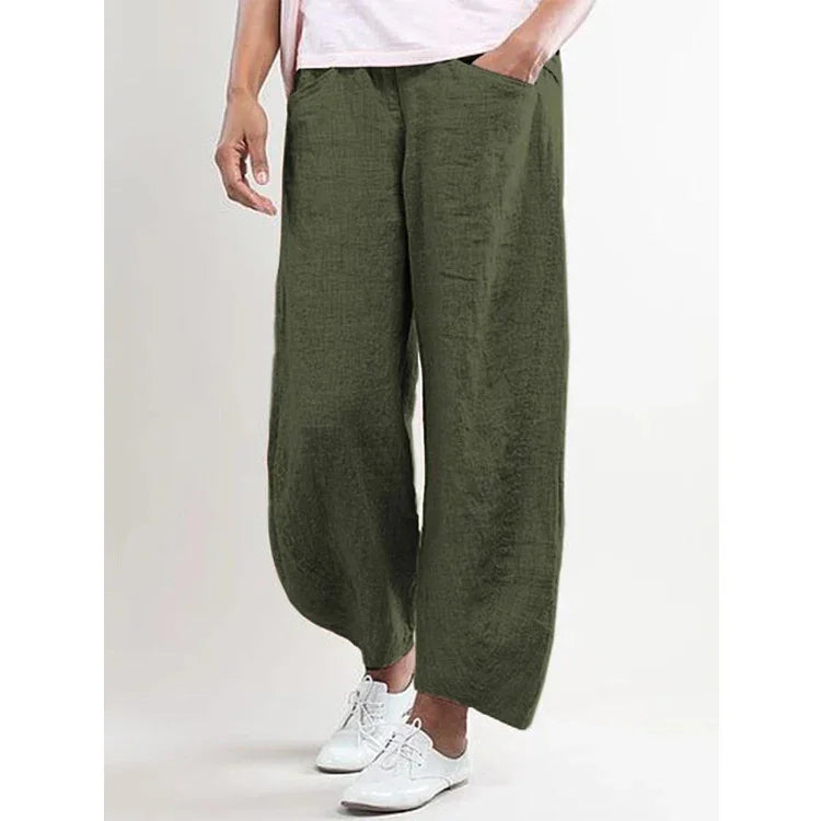 Loose fit olive green linen pants with pockets worn with white sneakers and a light pink top