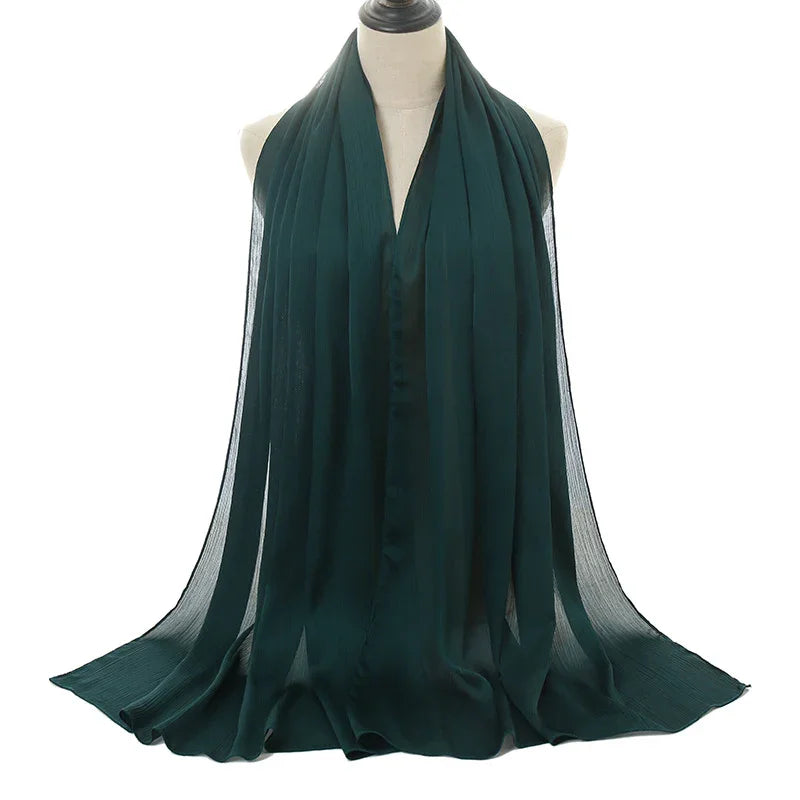 Dark green lightweight chiffon scarf draped on white mannequin against white background