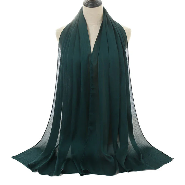 Dark green lightweight chiffon scarf draped on white mannequin against white background