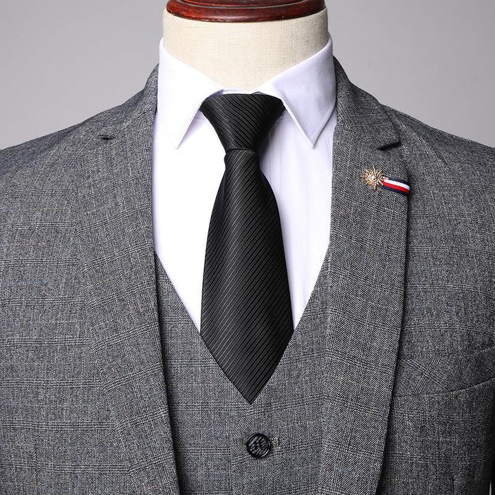 Gray plaid men's suit with white dress shirt, black tie, and decorative lapel pin on mannequin