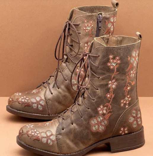 Brown leather lace-up boots with floral embroidery and side zipper on beige background