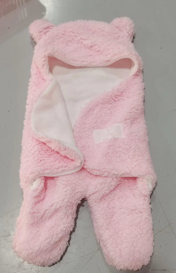 Soft pink fleece baby romper with hood and bear ears on gray floor