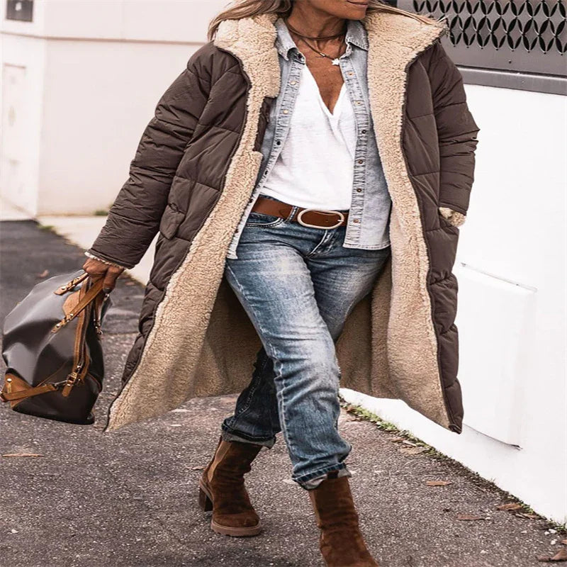 Woman walking in cozy brown sherpa-lined winter coat, white shirt, blue jeans, and brown ankle boots carrying stylish handbag