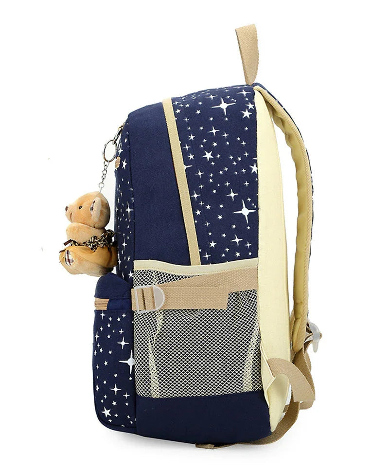 Navy blue star-print backpack with beige trim and side mesh pocket, featuring a small teddy bear keychain