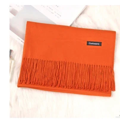 Bright orange cashmere scarf with fringe edges on white fluffy surface