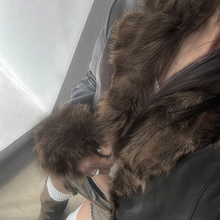 Person wearing a brown fur collar and cuffs on a black leather jacket with ripped jeans and white socks