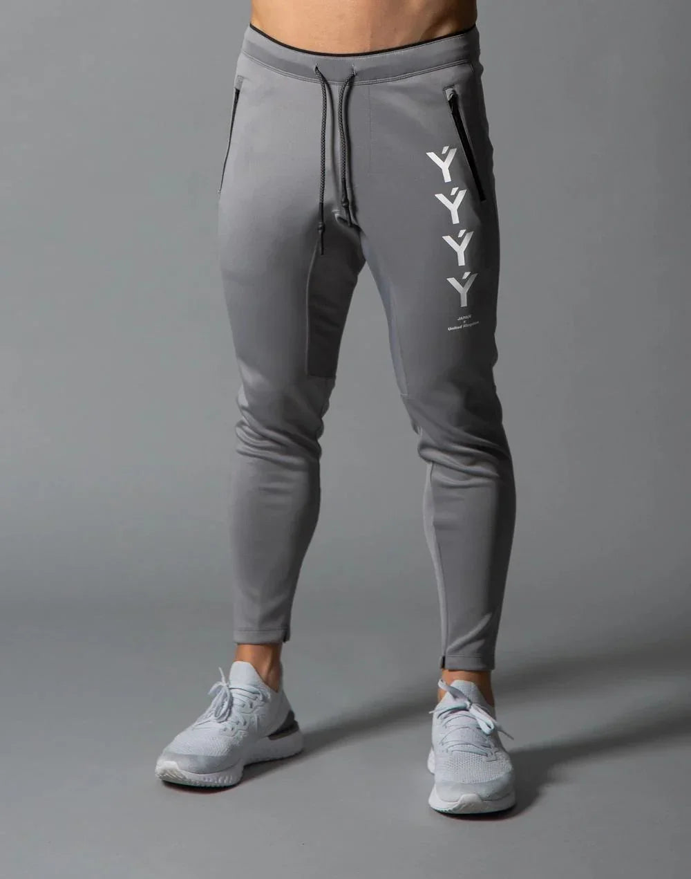 Men's gray slim-fit jogger pants with black zipper pockets and white YYY branding on thigh