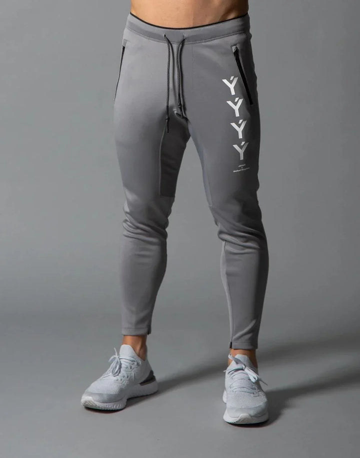 Men's gray slim-fit jogger pants with black zipper pockets and white YYY branding on thigh