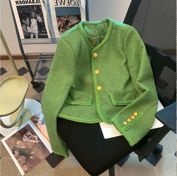 Green textured cropped blazer with gold buttons on a black office chair in a modern room