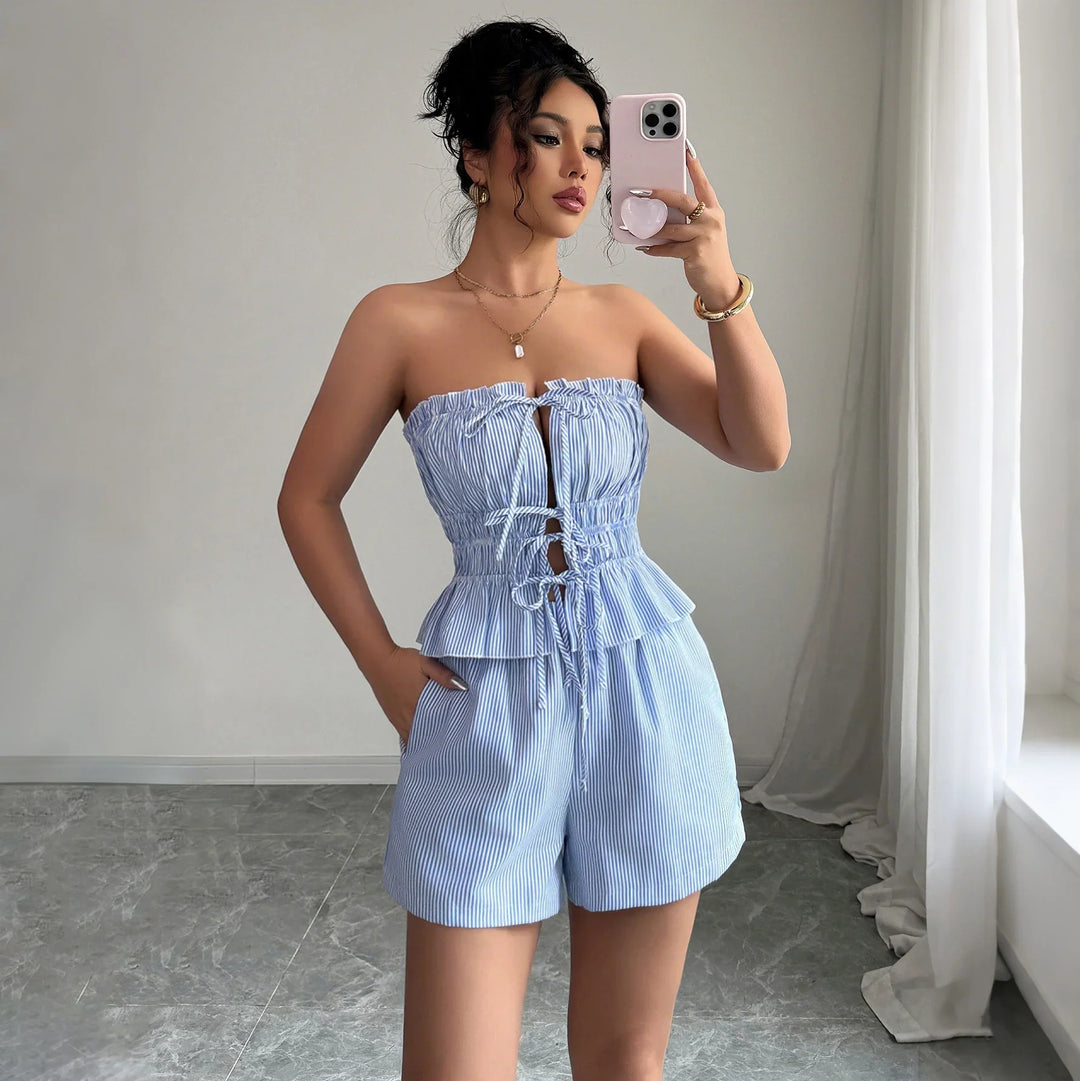 Woman in blue and white striped strapless ruffled top and shorts taking selfie in bright minimalist room