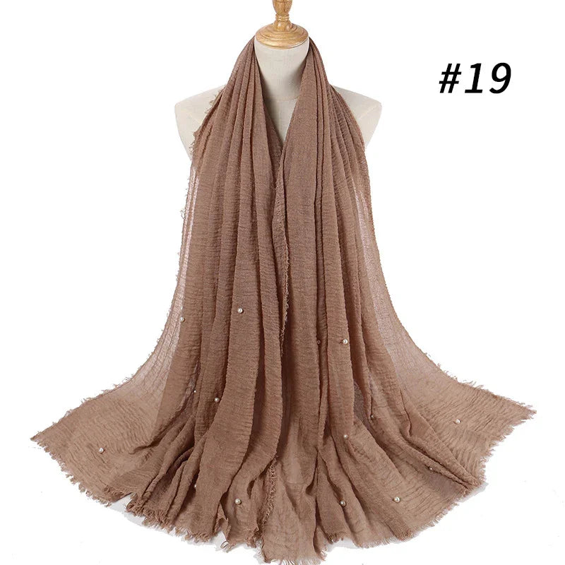 Light brown textured fabric scarf with small pearl embellishments displayed on a mannequin against white background