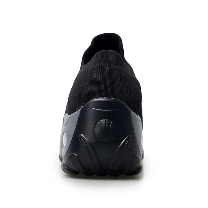 Rear view of black slip-on athletic sneaker with knit upper and textured sole on white background