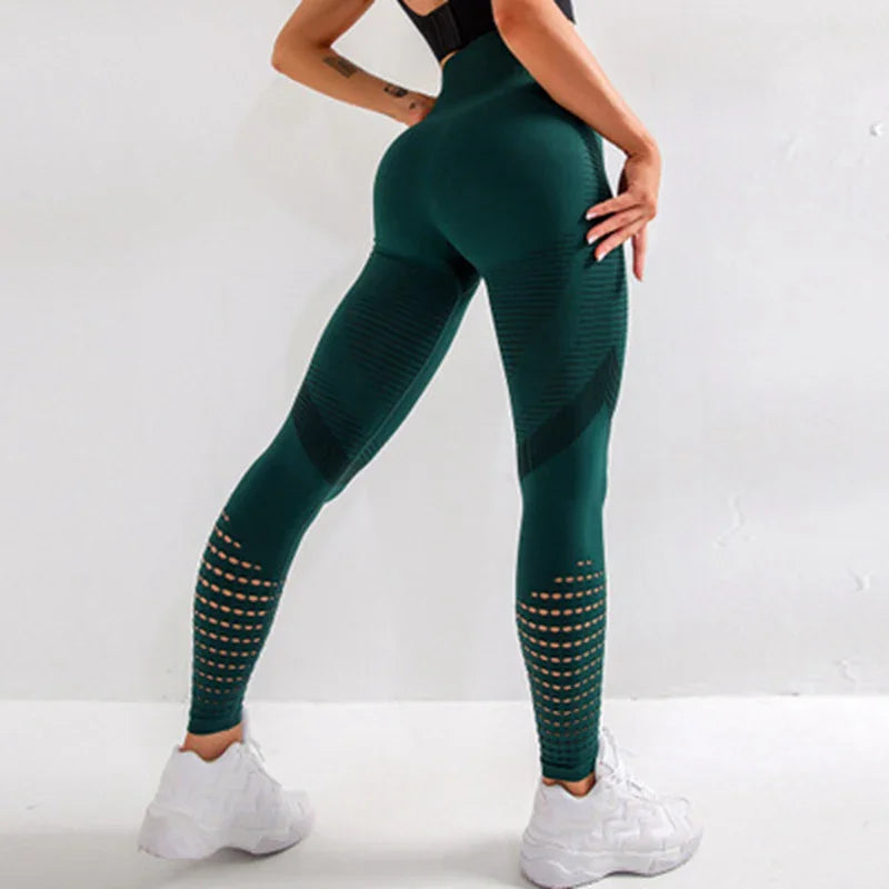 Woman wearing dark green textured seamless leggings with cutout patterns and white chunky sneakers against white background