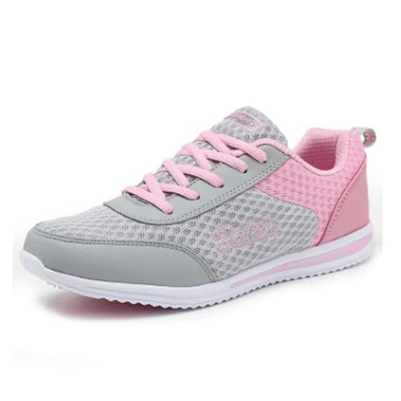 Light gray and pink women's athletic sneaker with mesh fabric and pink laces on white background
