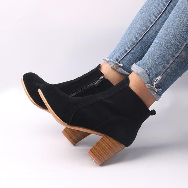 Black suede ankle boots with side zipper and wooden block heel worn with rolled-up blue skinny jeans