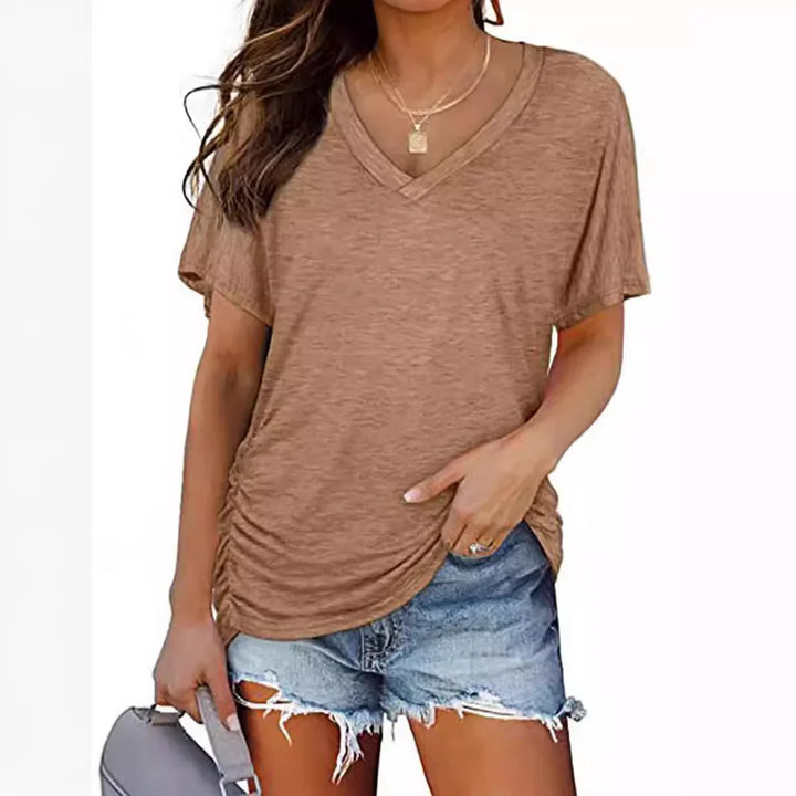 Woman wearing brown v-neck ruched side t-shirt and distressed denim shorts, holding gray handbag