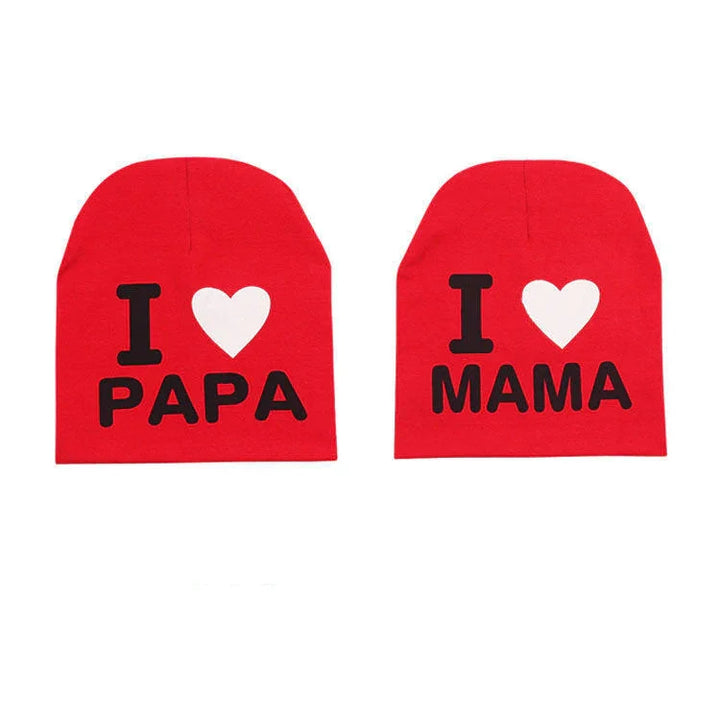 Red beanie hats with black text saying I heart PAPA and I heart MAMA, white heart icons