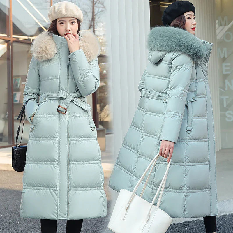 Two women in long light blue quilted winter coats with fur collars, one wearing a beige beret, the other a black beret, carrying handbags