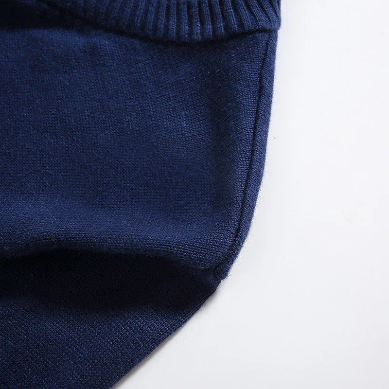 Close-up of navy blue knitted wool sweater with ribbed collar on white background