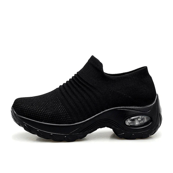 Black slip-on sneaker with knitted upper and thick cushioned sole featuring visible air cushion