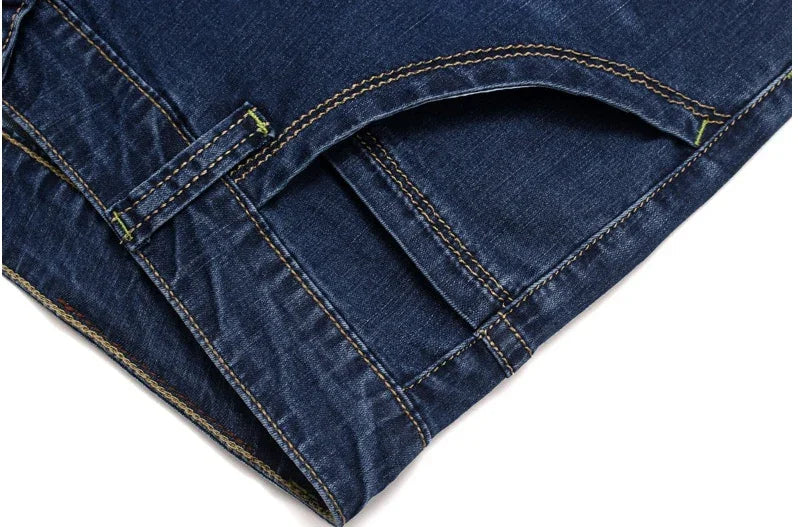 Close-up of dark blue denim jeans pocket with orange and yellow stitching details