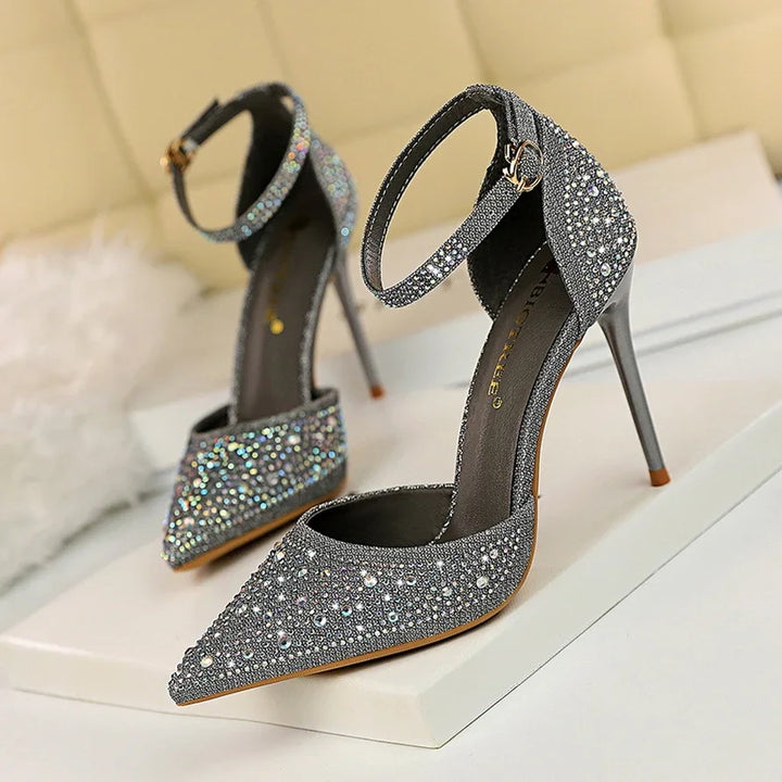 pair of silver high heel stiletto shoes with ankle straps and rhinestone embellishments