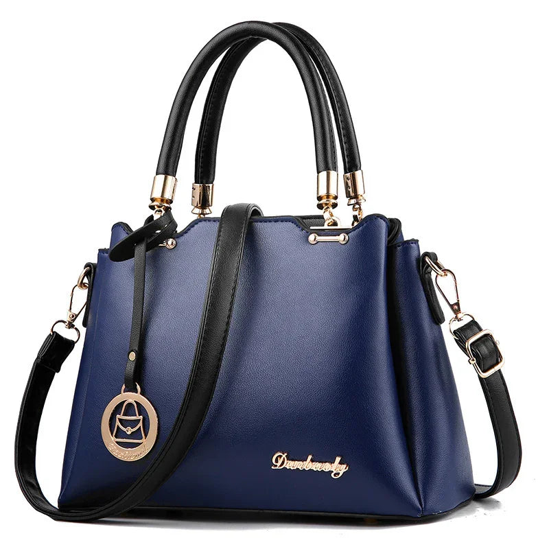 Stylish navy blue leather handbag with black handles and adjustable shoulder strap, gold accents