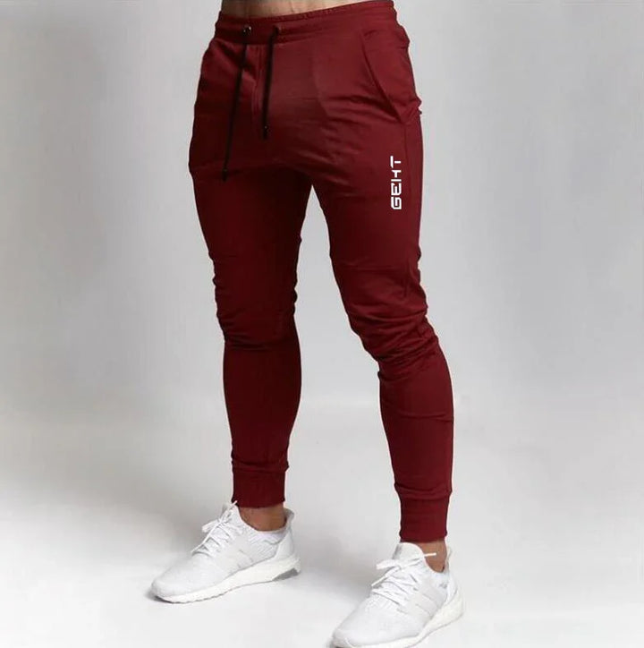 Men's slim fit maroon joggers with black drawstring and white sport shoes on white background