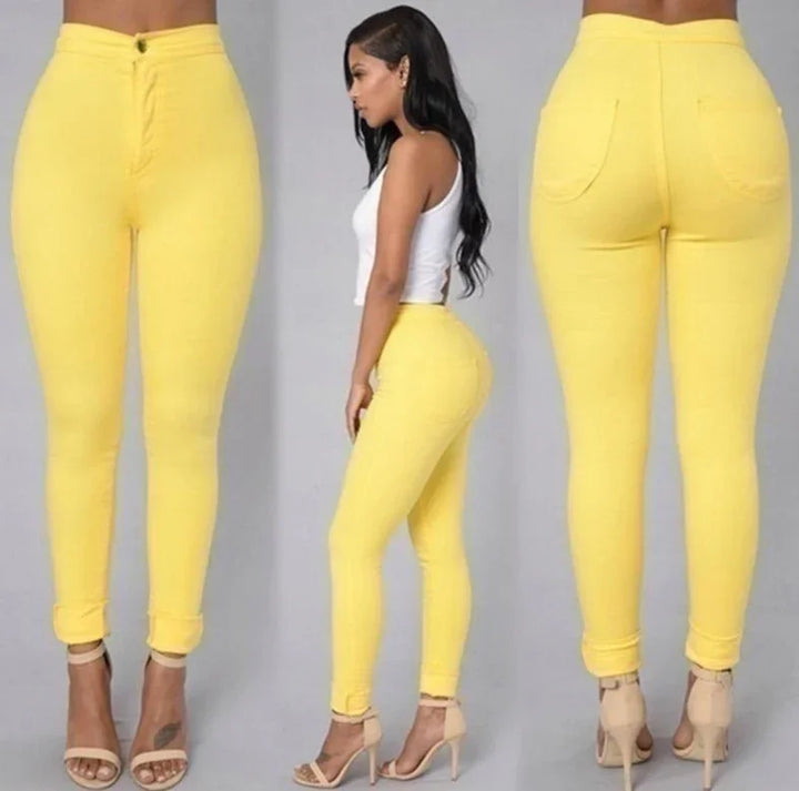 Woman modeling yellow high-waisted skinny jeans with rolled cuffs and beige high heels