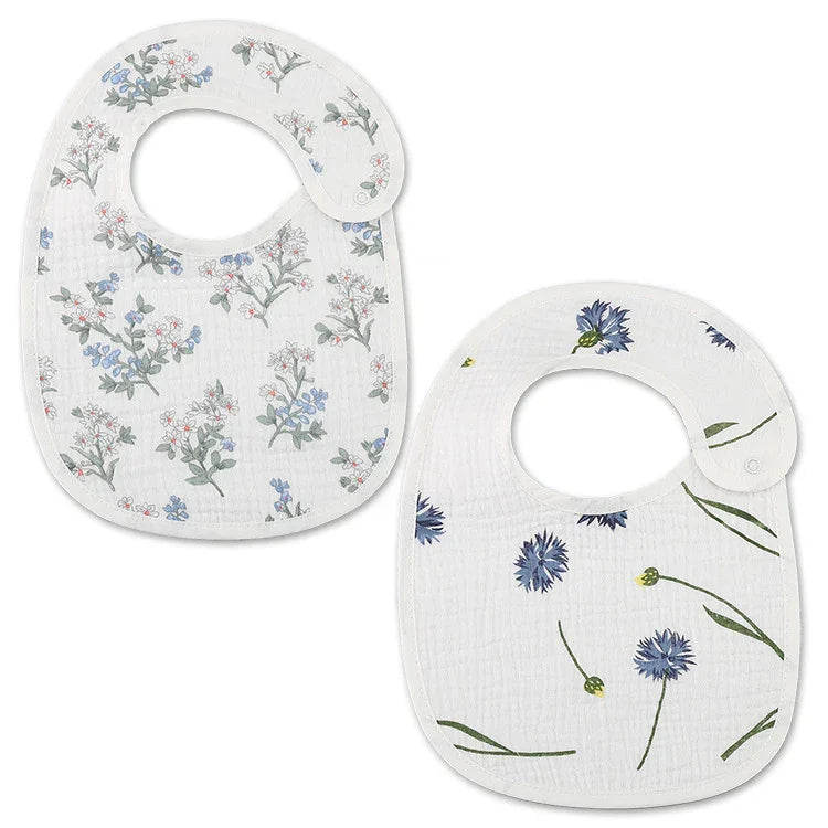 Two white baby bibs with floral prints, one with red and blue flowers, the other with blue flowers and green stems