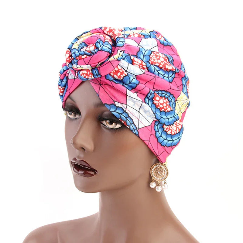  mannequin wearing a colorful pink floral African print headwrap turban with gold and pearl earrings