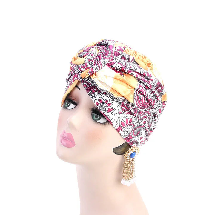woman mannequin head wearing colorful paisley turban headwrap and gold tassel earrings