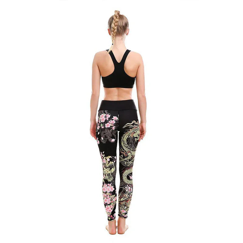 Woman wearing black sports bra and black leggings with colorful dragon and floral print, standing barefoot