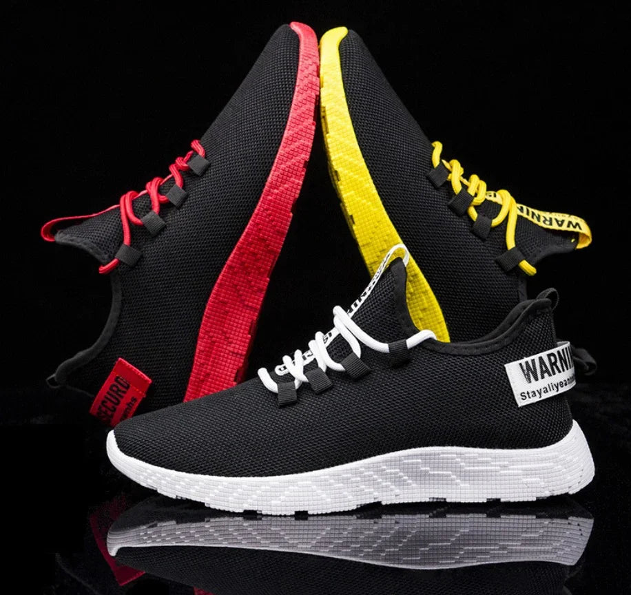 Black mesh sneakers with red, yellow, and white soles and laces on black background