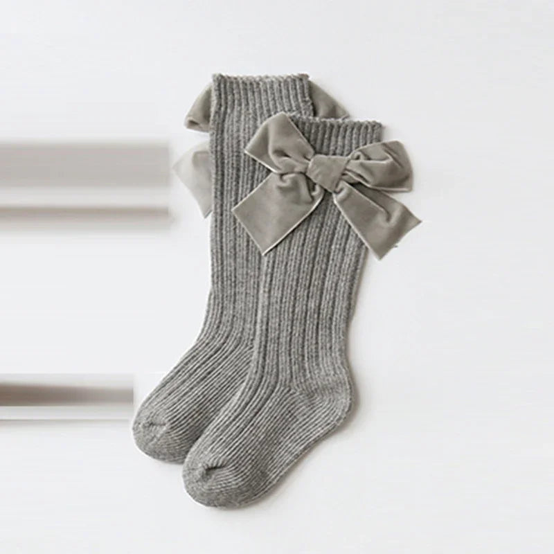 Pair of grey ribbed knit socks with large velvet bows on the sides