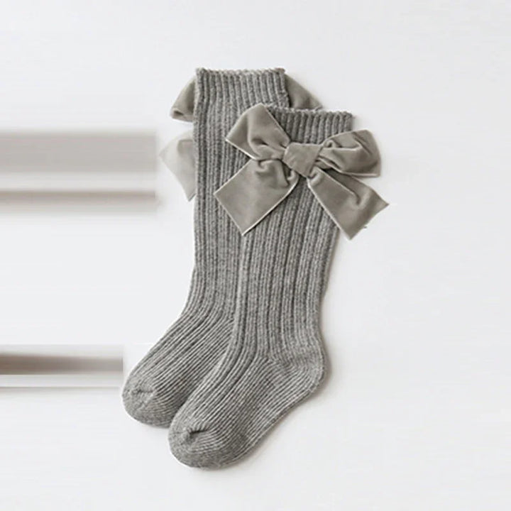 Pair of grey ribbed knit socks with large velvet bows on the sides