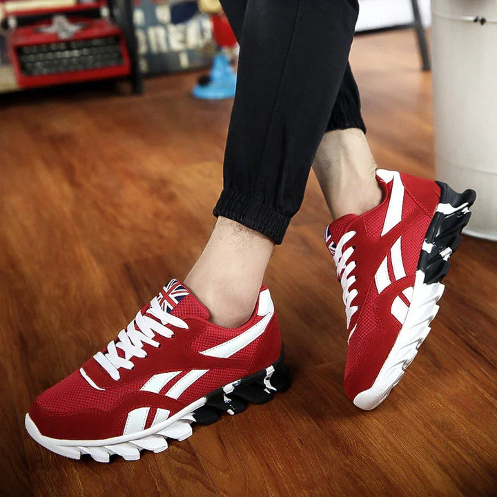 Red and white athletic sneakers with unique black and white sole design worn with black jogger pants on wooden floor
