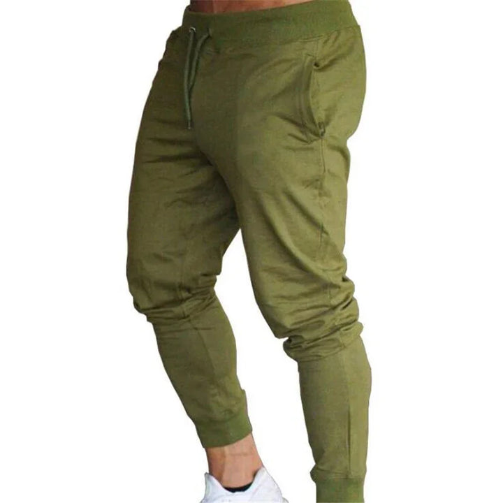 Men's olive green jogger pants with drawstring waist and side pockets, worn with white sneakers