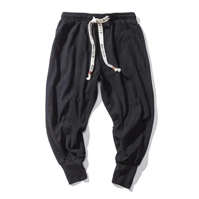 Black casual jogger pants with elastic cuffs and white drawstring featuring black script