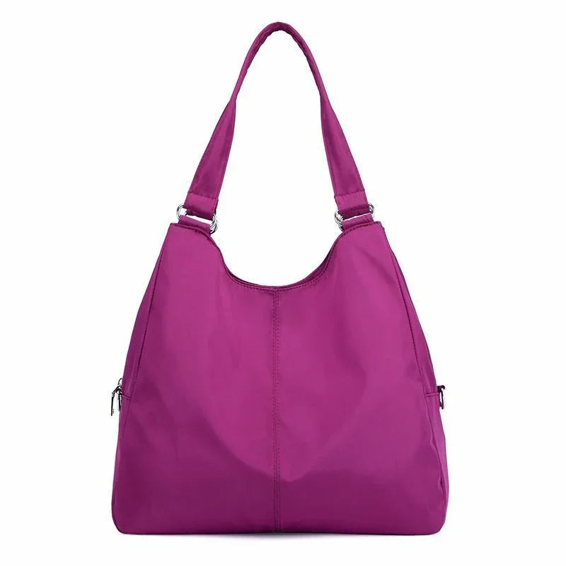Purple nylon shoulder bag with double strap and side zipper pockets on white background