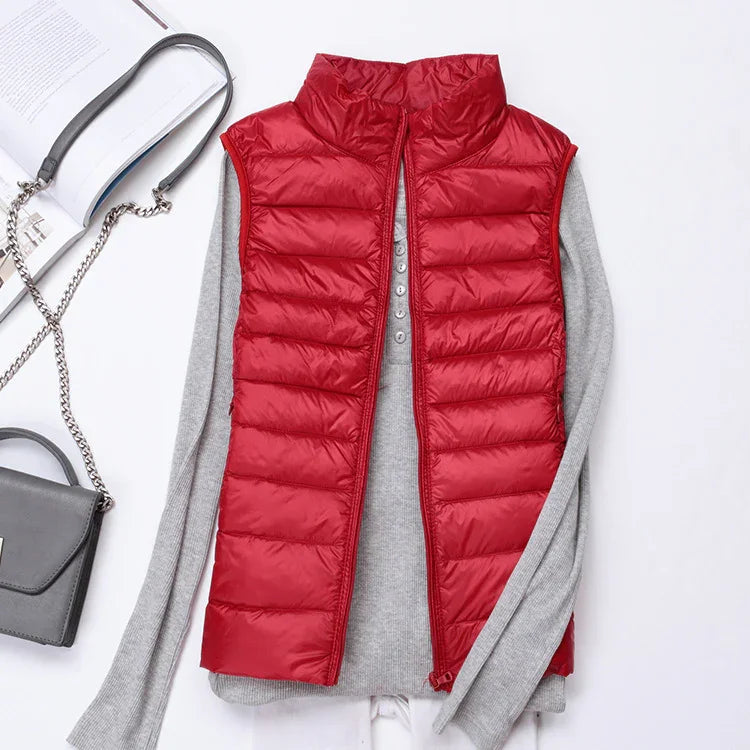 Red puffer vest layered over a gray long-sleeve sweater, styled with a gray chain strap handbag and open book