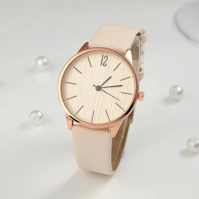 elegant beige leather strap wristwatch with rose gold case and minimalist dial on white surface