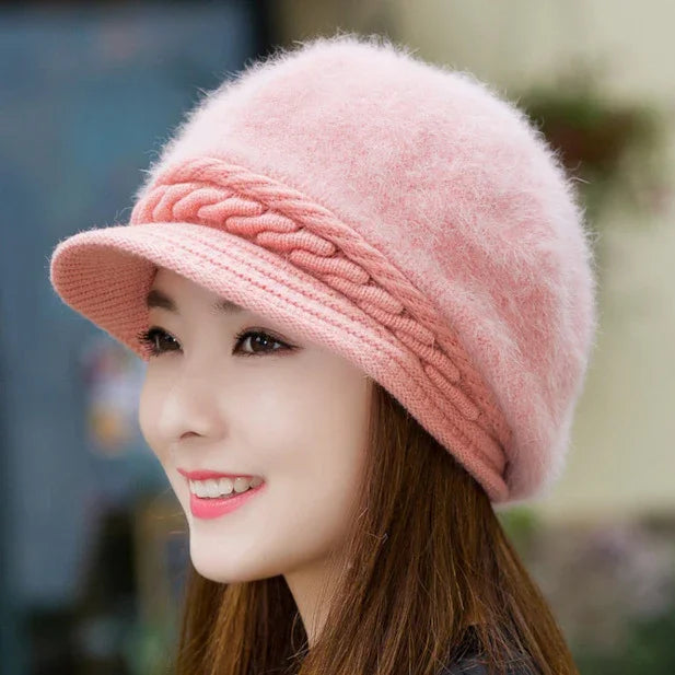 Woman wearing soft pink fuzzy knit hat with braided band and short brim, smiling outdoors