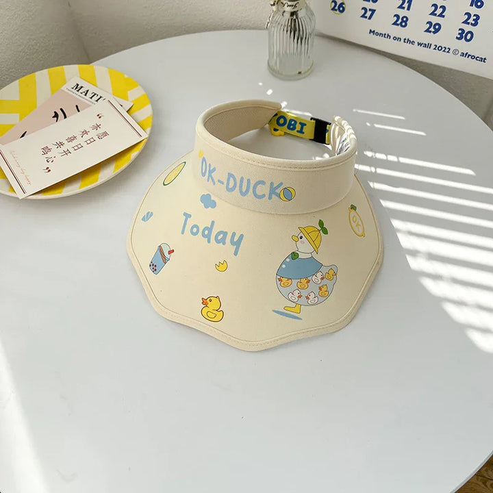 Beige visor hat with cute duck and bubble tea print, text OK-DUCK Today, on white round table