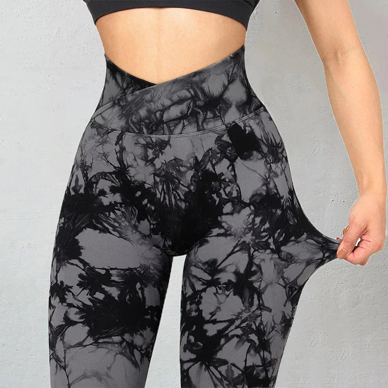 Close-up of woman wearing high-waisted black and gray tie-dye leggings stretching fabric