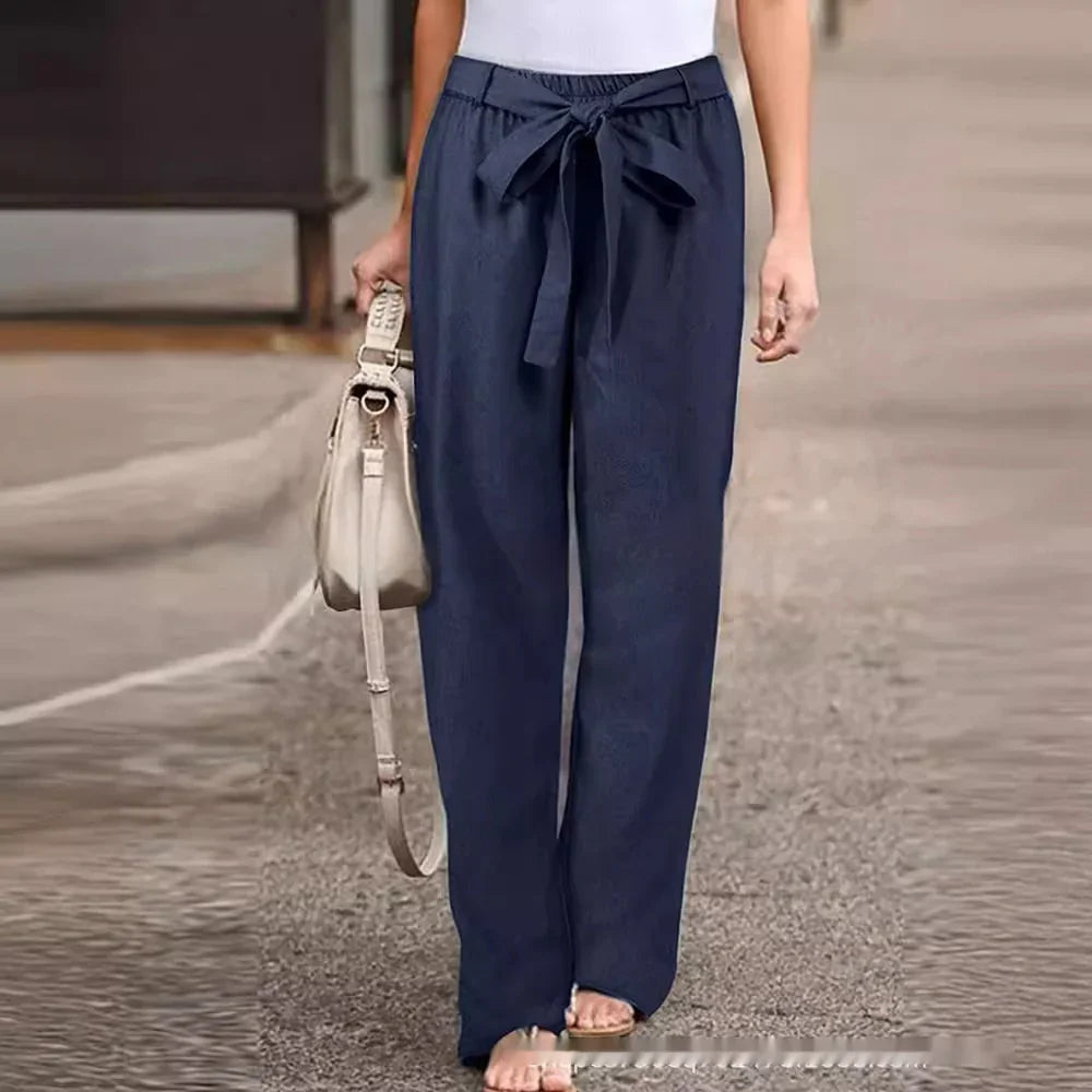 woman wearing navy blue high-waisted wide-leg pants with a front tie belt walking on city sidewalk