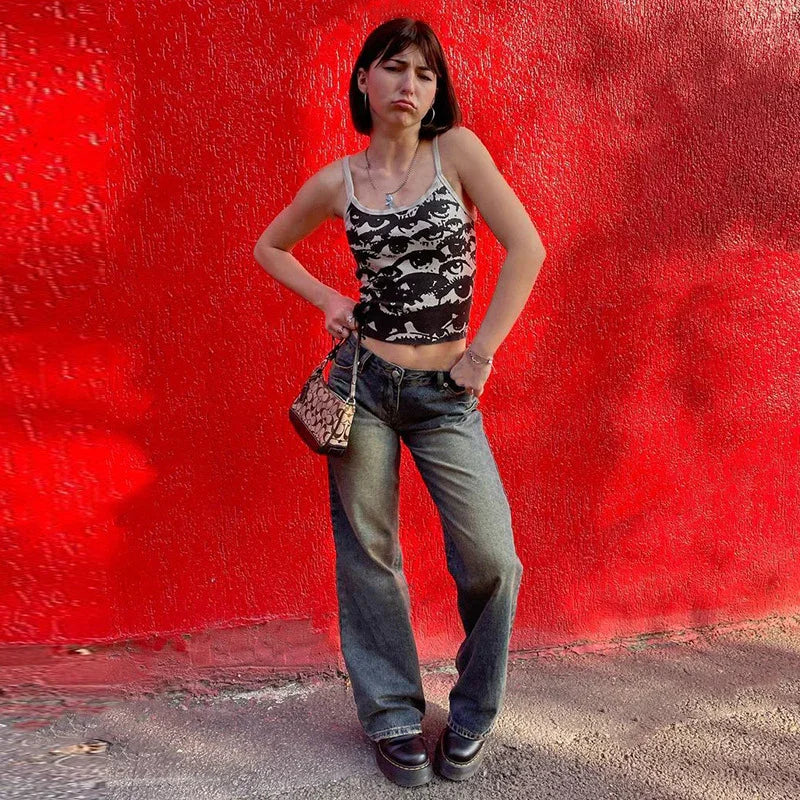 Young woman in black and white eye-print tank top and wide-leg jeans posing against vibrant red wall