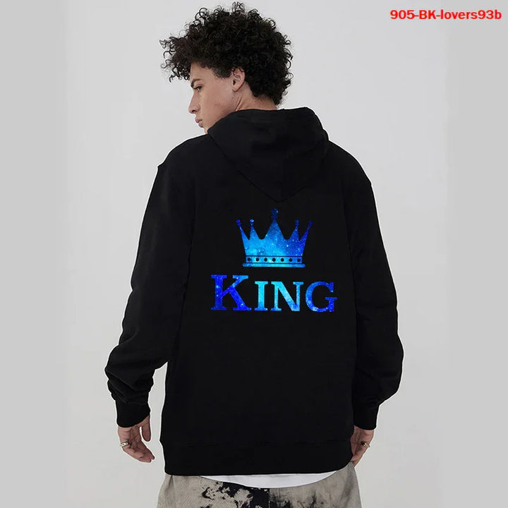 Man wearing black hoodie with blue crown and King text graphic on back in casual studio setting